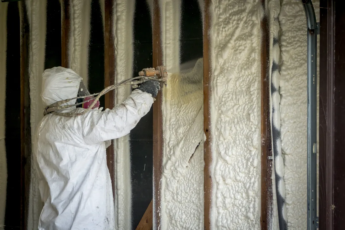 Application de mousse isolante sur les murs d'une structure pour une isolation thermique performante.